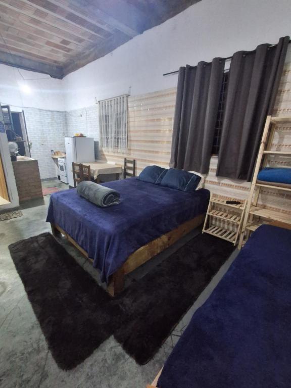 a bedroom with a large bed with blue sheets and blue pillows at Mahaidana Kitnet in São Thomé das Letras