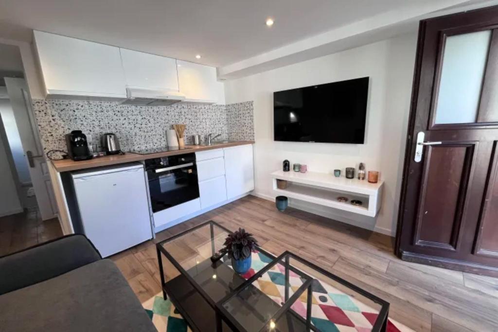 eine Küche mit weißen Schränken und einem TV an der Wand in der Unterkunft Soh Rent Appartement Schiltigheim proche Strasbourg terrasse -Tv in Schiltigheim