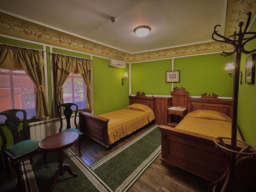 a bedroom with two beds and a table and chairs at Family Hotel at Renaissance Square in Plovdiv