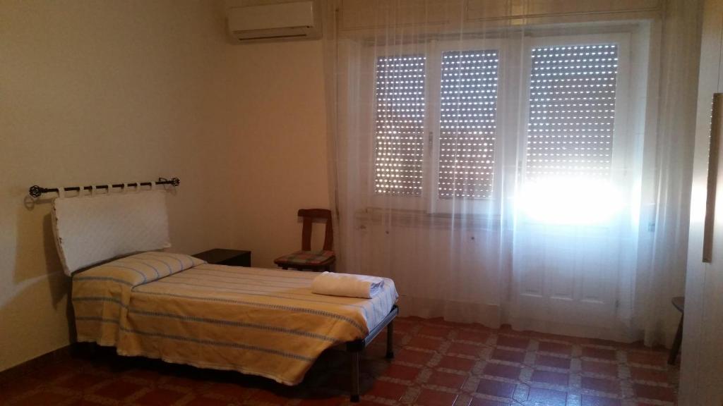 a bedroom with a bed and a window with white curtains at Appartamento Alemù in Olbia