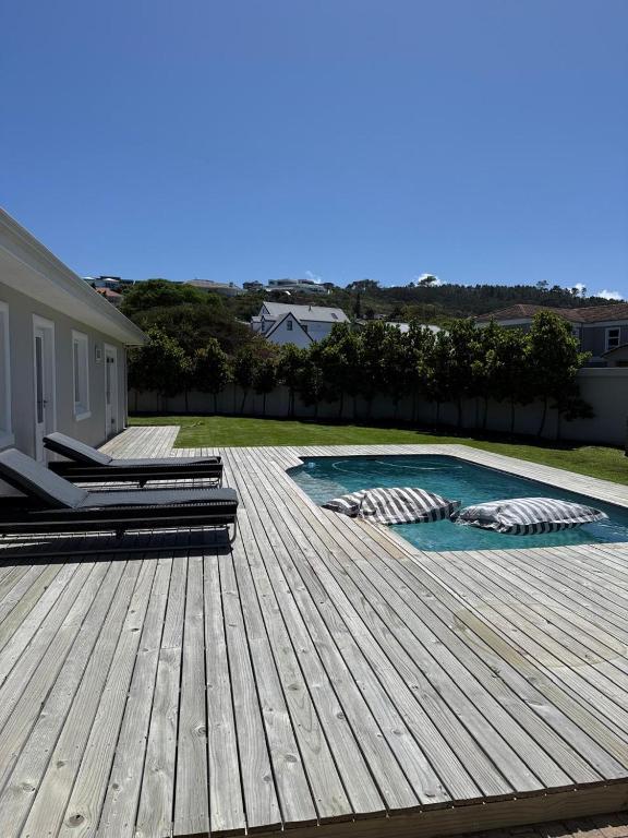a wooden deck with chairs and a swimming pool at 1 Diadem in Plettenberg Bay
