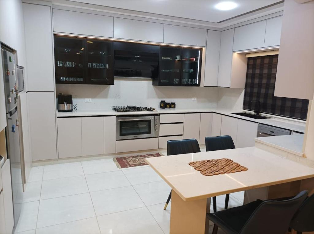 a kitchen with white cabinets and a table with chairs at لا يمكن حجزه in Irbid