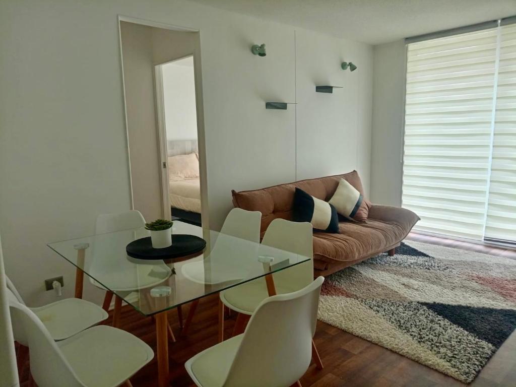 a living room with a glass table and white chairs at Departamento en Pucón in Pucón