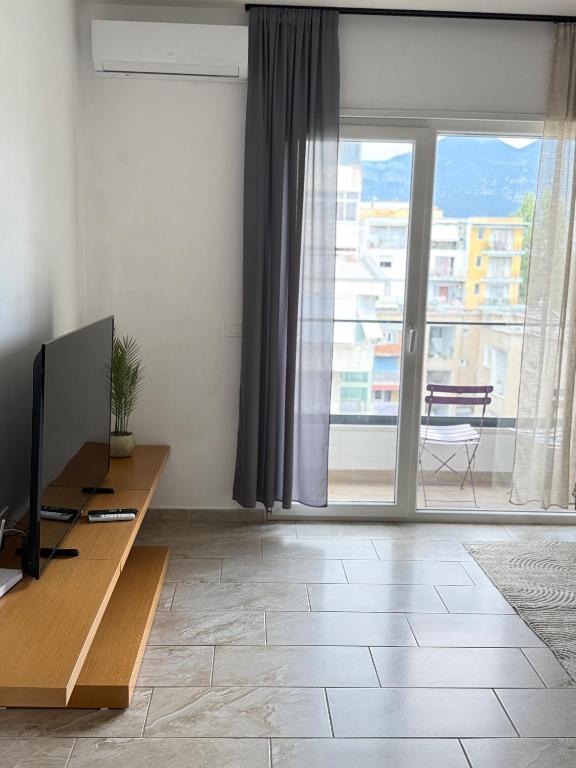 a living room with a television and a large window at Bejart Apartment 7 in Tirana