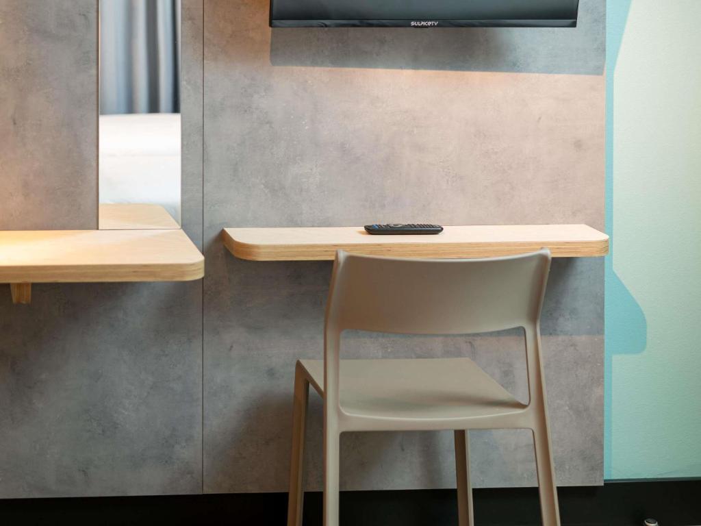 une chaise assise à côté d'une table et d'une télévision dans l'établissement Ibis Budget Lyon Caluire Cité Internationale, à Caluire-et-Cuire