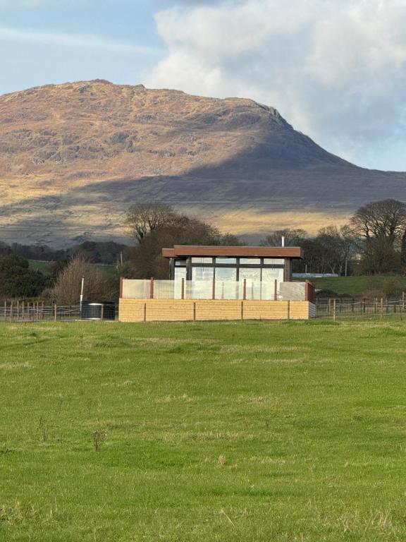 a building in a field with a mountain in the background at Loughanmore Court Beach house in Dundalk