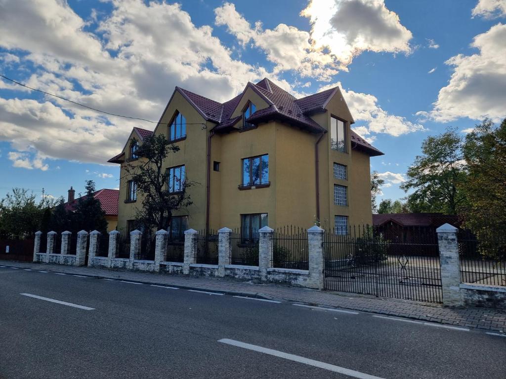 a large yellow house with a fence on the side of the road at Elysium Zenith Estate in Cornu de Jos