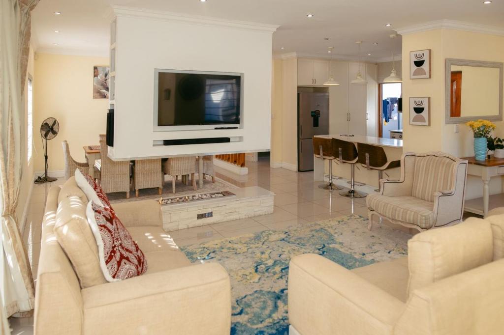 a living room with a couch and a tv and a kitchen at Lovely and Peaceful 3 bedroom house in Cape Town