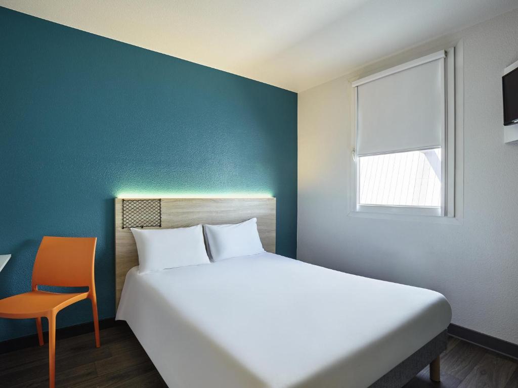 Un dormitorio con una cama grande y una silla. en hotelF1 Bayonne, en Bayona