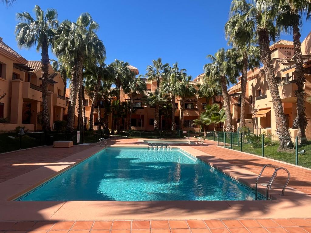 une piscine dans une cour avec des palmiers dans l'établissement Casa Vera - apartment in Los Alcázares - Nueva Ribera Beach Club, à Los Alcázares