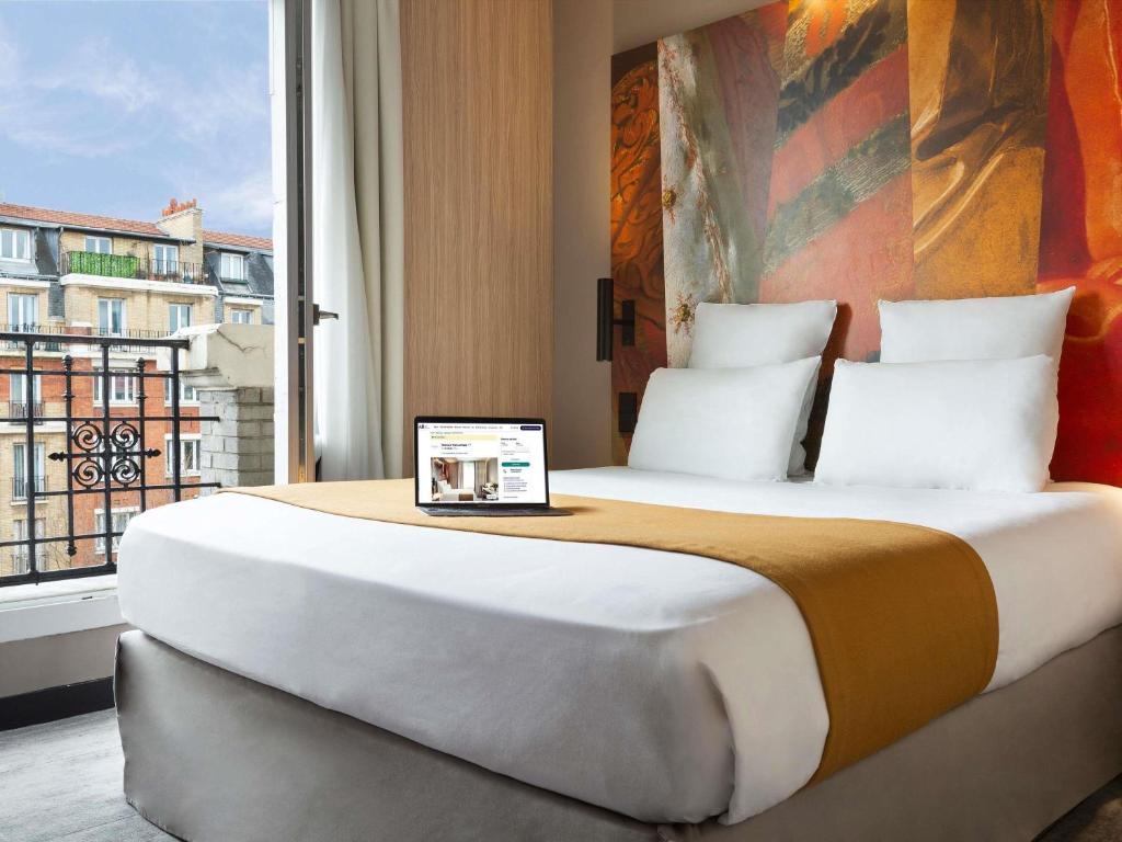 une chambre avec un grand lit avec une grande fenêtre dans l'établissement Mercure Paris Alesia, à Paris
