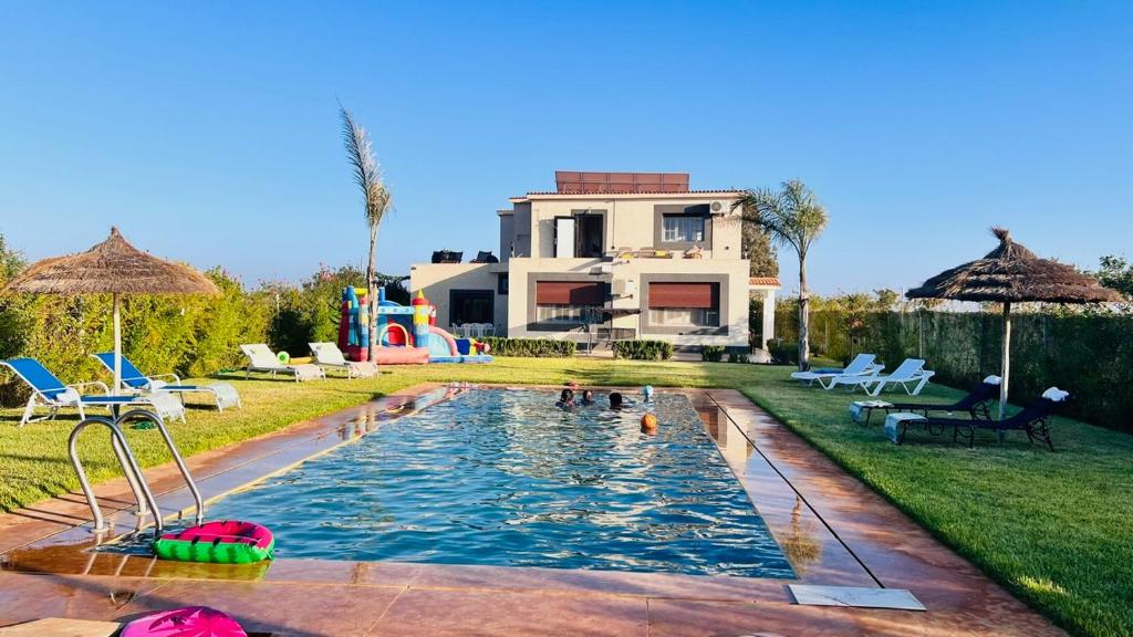 a swimming pool in a yard with a house at Ferme royale Bensliman in O Ben Slimane