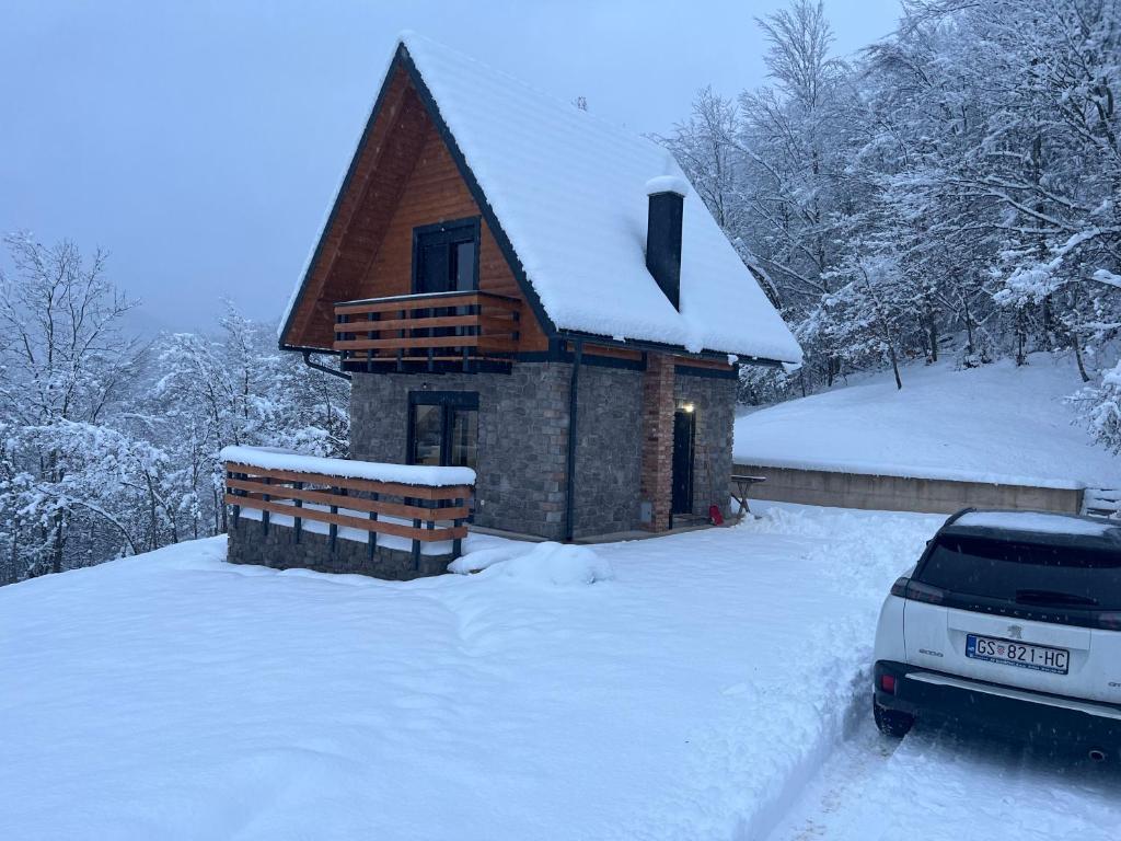 une cabine enneigée avec une voiture garée devant elle dans l'établissement Kuća za odmor LO, à Lipovlje