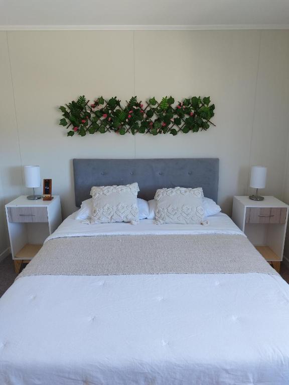 a bedroom with a large white bed with two night stands at Cabaña Villarrica Los Carpinteros in Villarrica