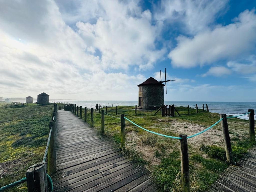 a wooden boardwalk leading to a windmill on the beach at ApuliaMar Apartment in Apúlia