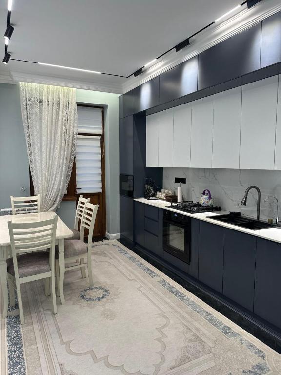 een keuken met witte kasten en een tafel en stoelen bij Prime House Samarkand 2 in Samarkand