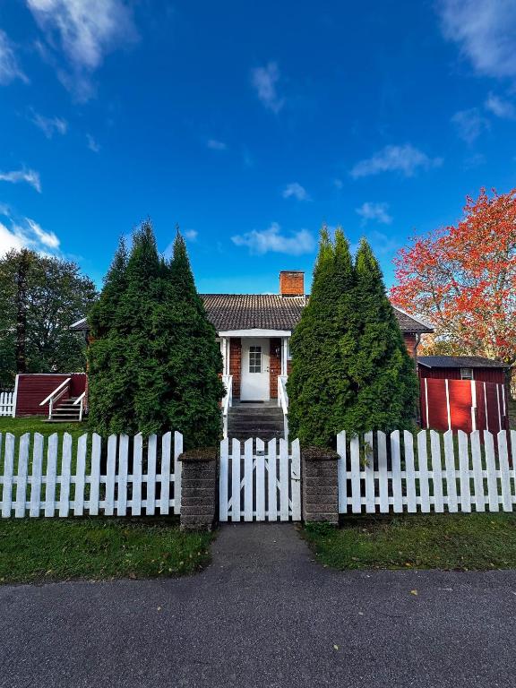 a white fence in front of a house with trees at FoRest House in Rosenfors