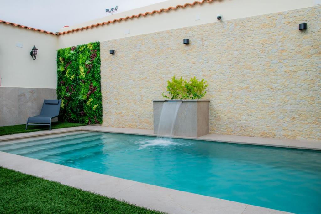 een zwembad met een stoel naast een bakstenen muur bij Casa Rural La Bodega de Cortés in Villagonzalo