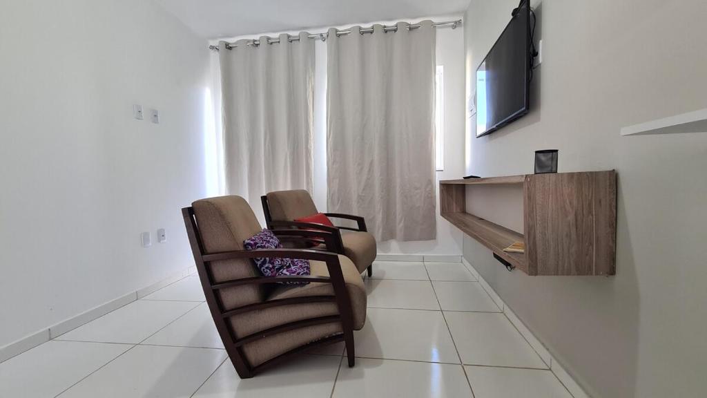 a living room with two chairs and a flat screen tv at Casa 66 Completa Garagem 2ACs WIFI Juazeiro, Crato e Barbalha in Barbalha