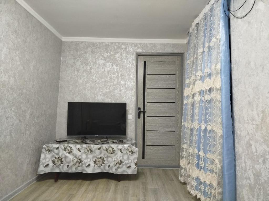 Zimmer mit einem TV und einem Tisch mit einem TV. in der Unterkunft Дом in Taschkent