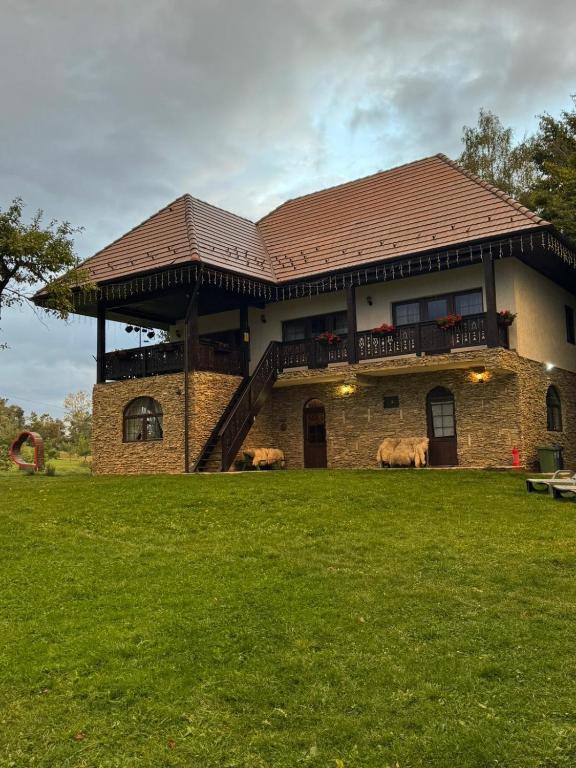 a large brick house with a deck on top of it at Casa meșterului in Sohodol