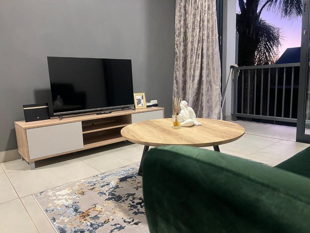 Una sala de estar con televisión y una mesa de café. en Modern Apartment in Centurion, en Centurion