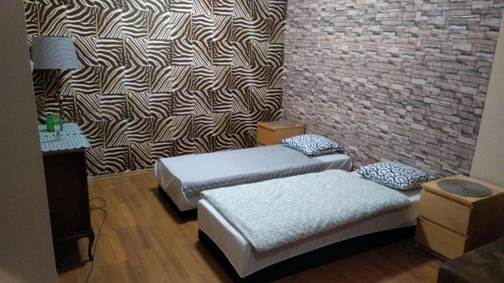 two beds in a room with a brick wall at FEIDUM quarters flat in Kraków