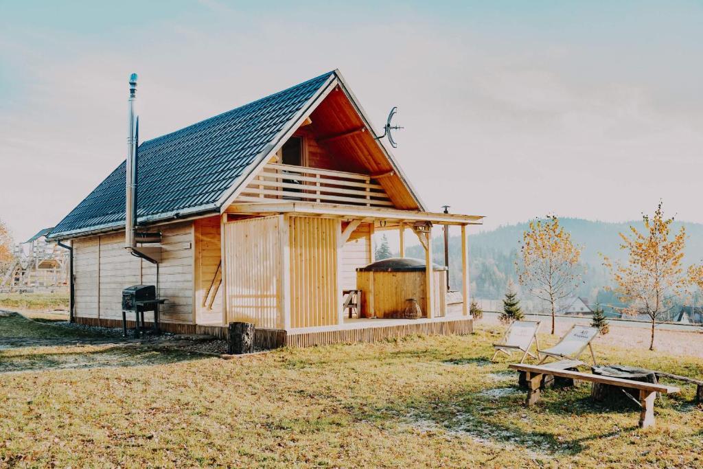 ein kleines Holzhaus auf einem Feld mit einer Bank in der Unterkunft Domki pod Halą Krupową in Ohłypów