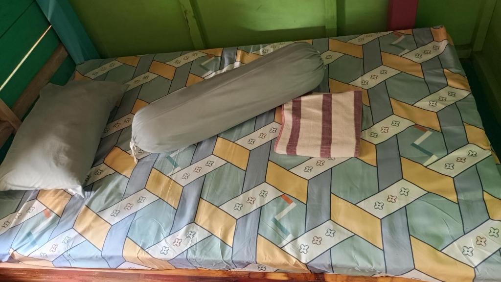 a bed with a quilt and a pillow on it at Surf House in Pulau Sarang