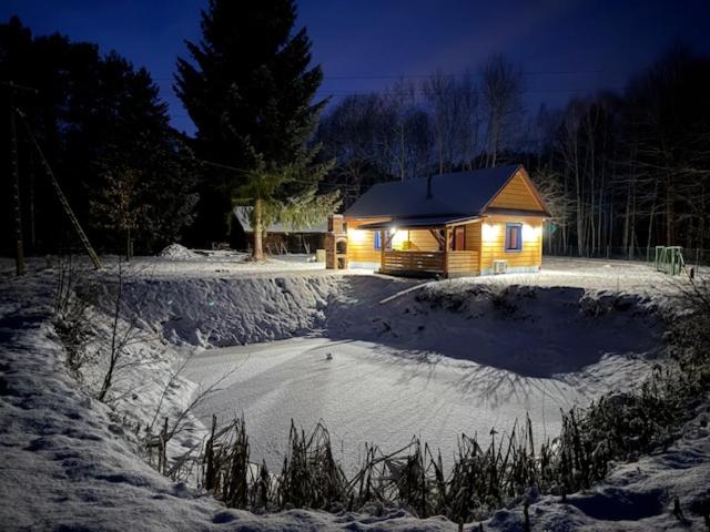 にあるRanczo Stanyの夜の雪の中のログキャビン