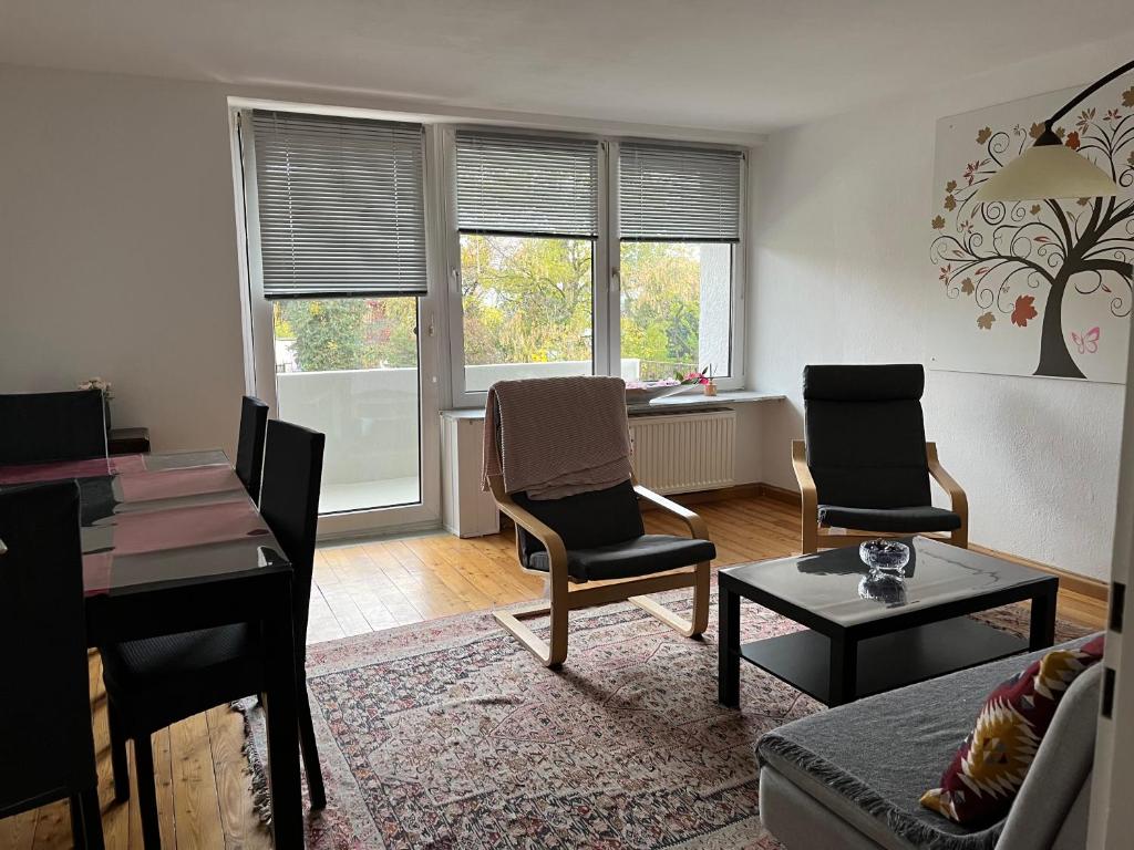 a living room with chairs and a table and windows at Ferienwohnung in Landsberg am Lech in Landsberg am Lech