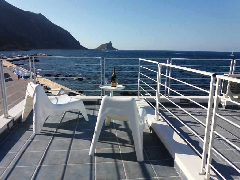 a balcony with two white chairs and a bottle of wine at Scalovecchio in Marettimo