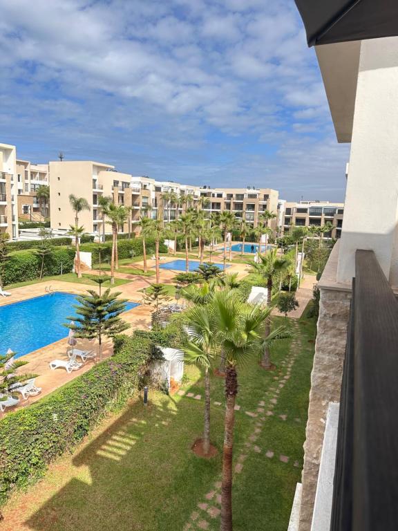 a view of a resort with a pool and palm trees at Appart familial avec terrasse et piscine, à 2 pas de la plage des nations - Rabat in Sidi Bouqnadel