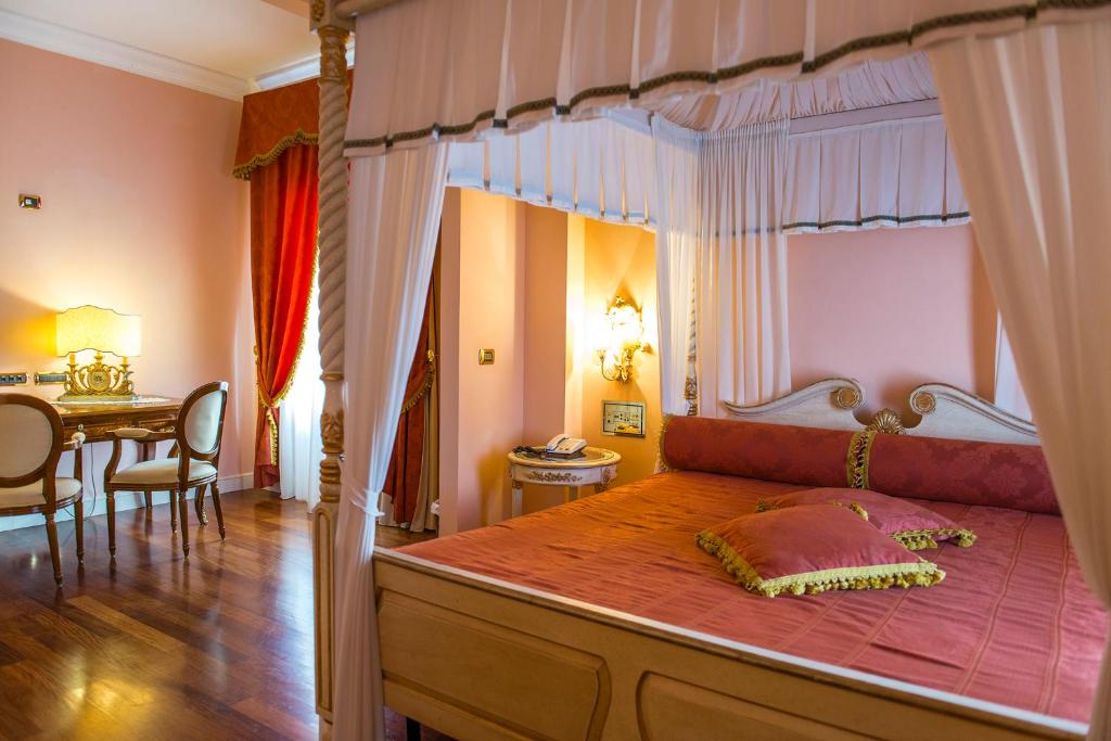 a bedroom with a canopy bed with a dining table at Hotel Villa Il Patriarca in Chiusi
