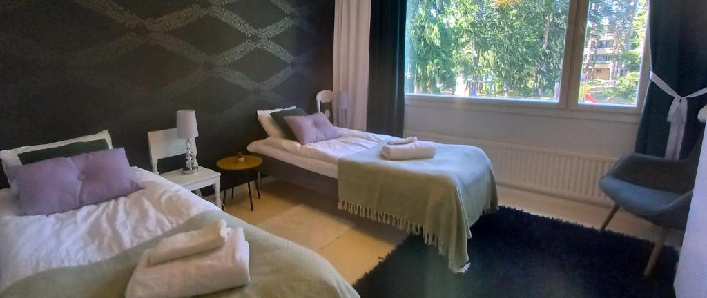 a hotel room with two beds and a window at Avara huoneisto, lasitettu parveke, kaksi weeceetä in Kotka