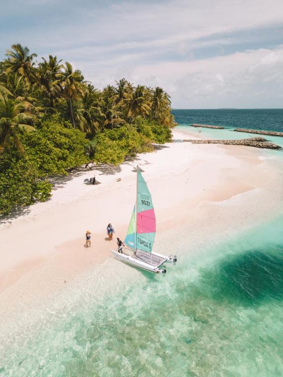people on a sailboat on a beach in the ocean at Dhoani Maldives Guesthouse in Kendhoo