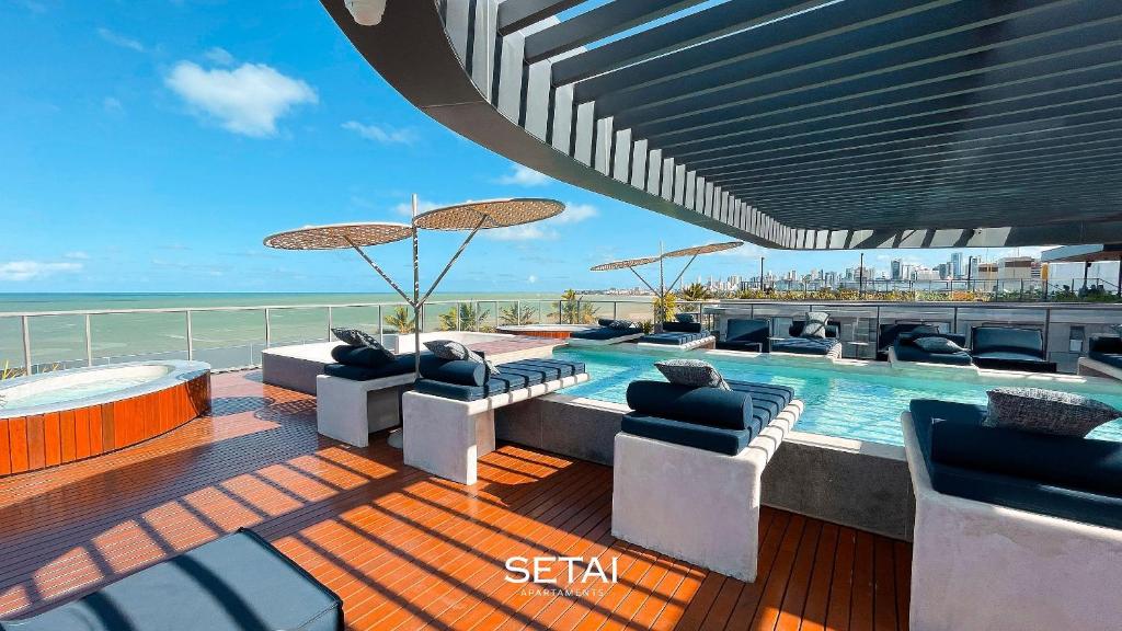 a swimming pool on a deck with chairs and an umbrella at Setai Aquamaris by Setai Apartaments in João Pessoa
