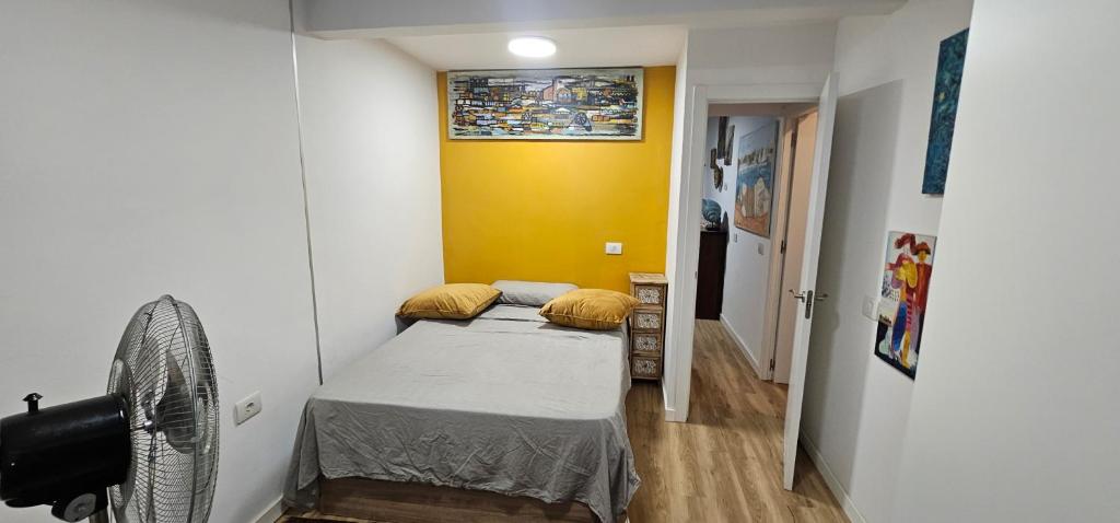 une petite chambre avec un lit et un mur jaune dans l'établissement Descanso cerca del mar, à Las Galletas