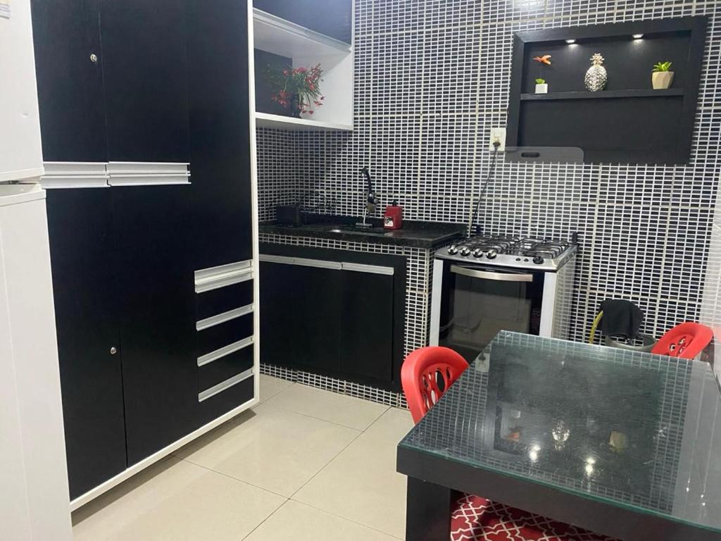 uma cozinha com armários pretos e uma mesa com cadeiras vermelhas em Casa completa em cabo frio em Cabo Frio