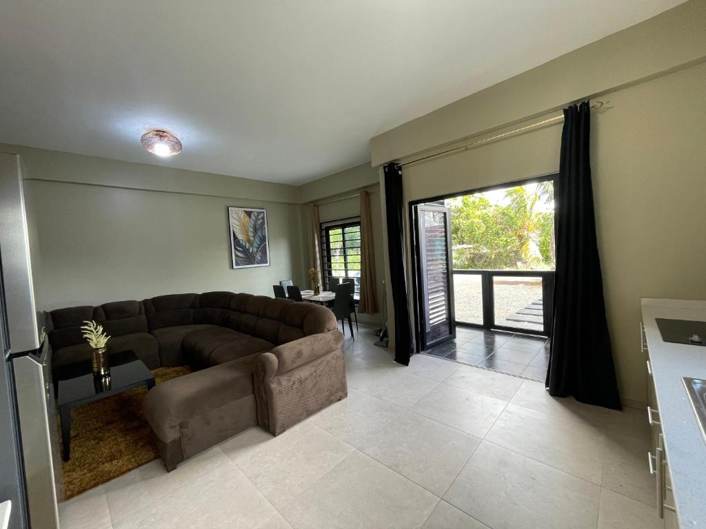 een woonkamer met een bruine bank en een glazen schuifdeur bij Majestic Apartment 1 Tout lui Faut in Flora