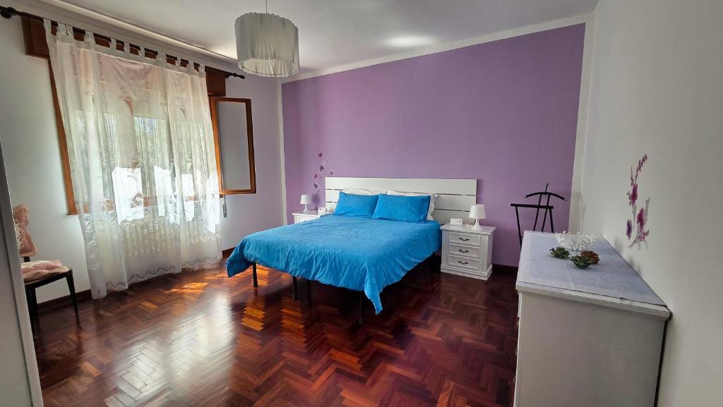 a bedroom with a blue bed and a purple wall at Casa Kendra in Montegrotto Terme