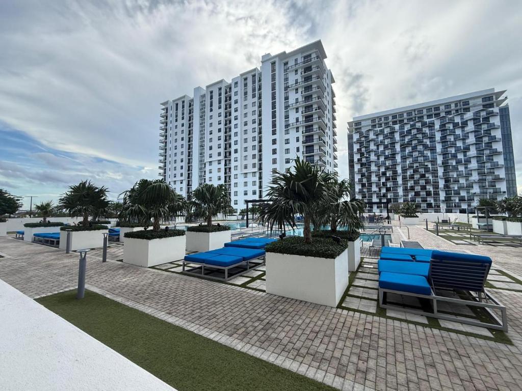 a large apartment building with blue chairs and palm trees at Bonito doral in Miami