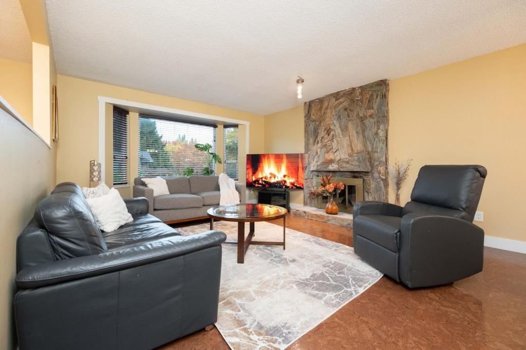 - un salon avec deux fauteuils en cuir et une cheminée dans l'établissement Cozy 3BR Family Home near City Centre & SkyTrain, à Coquitlam