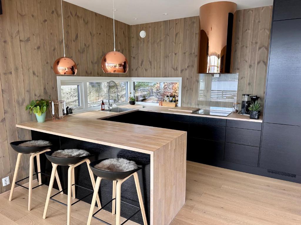 a kitchen with a wooden counter and stools in it at Delikat, moderne og komfortabel hytte med panoramautsikt over Nisser in Fjone