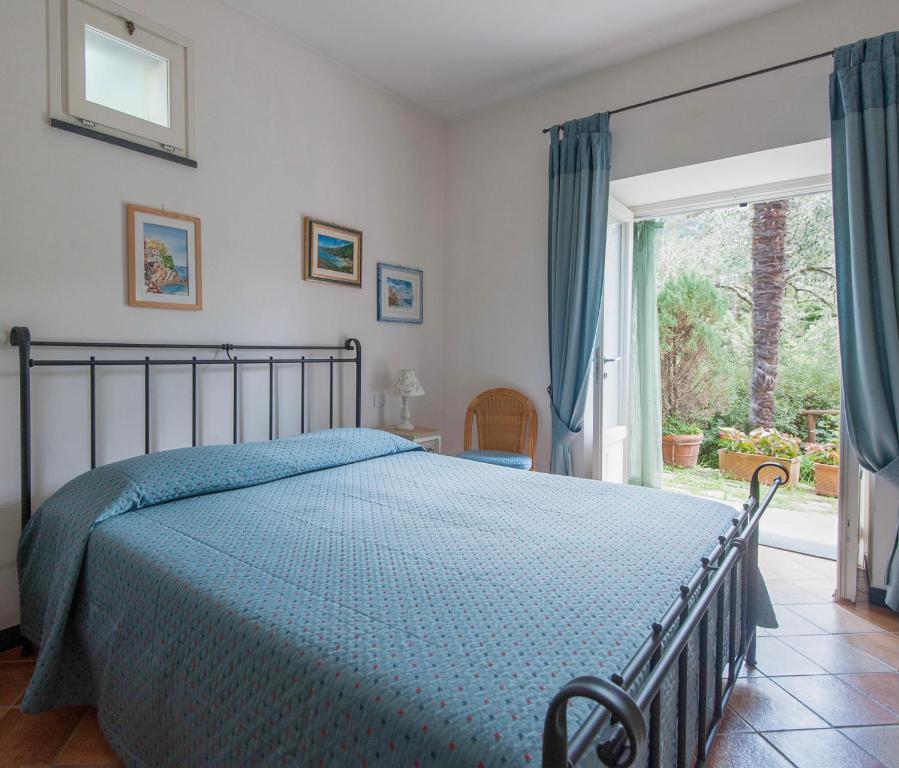 ein Schlafzimmer mit einem Bett mit einer blauen Bettdecke in der Unterkunft Agriturismo Villa Caterina in Levanto