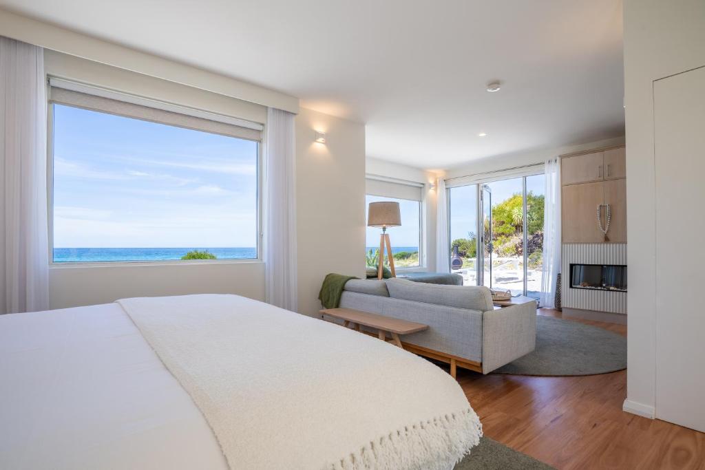 a bedroom with a bed and a couch and a large window at Saltwater - Absolute Oceanfront, Fire Pits, some Villas with Hot Tubs and Sauna in Falmouth
