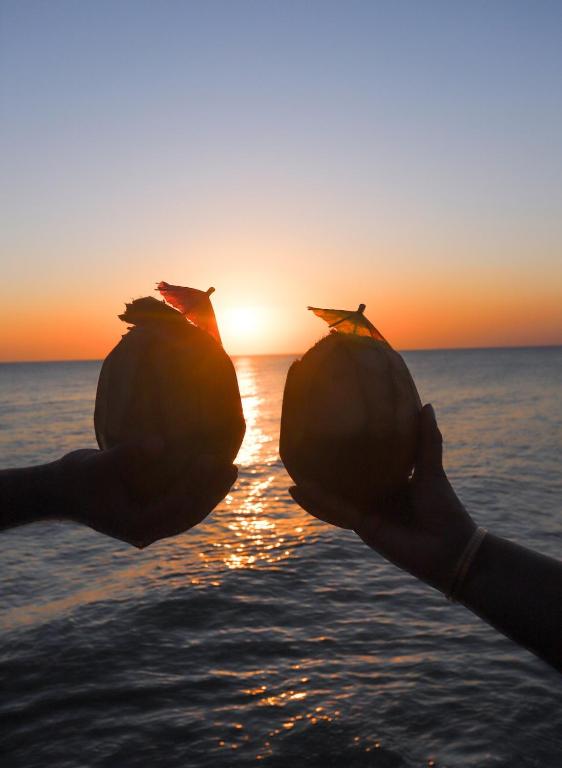 a person holding up two large containers in the ocean at Emerald Sunset Villa in Zanzibar City