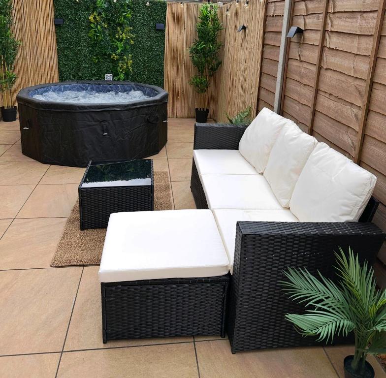 a patio with a couch and a hot tub at The Hidden Garden Gate Cabin in Wallington