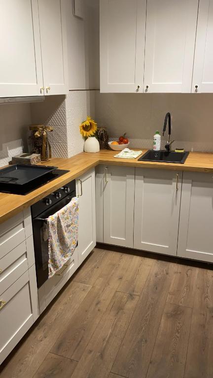 une cuisine avec des armoires blanches et un plancher en bois dans l'établissement Apartament Suwałki Szpitalna, 
