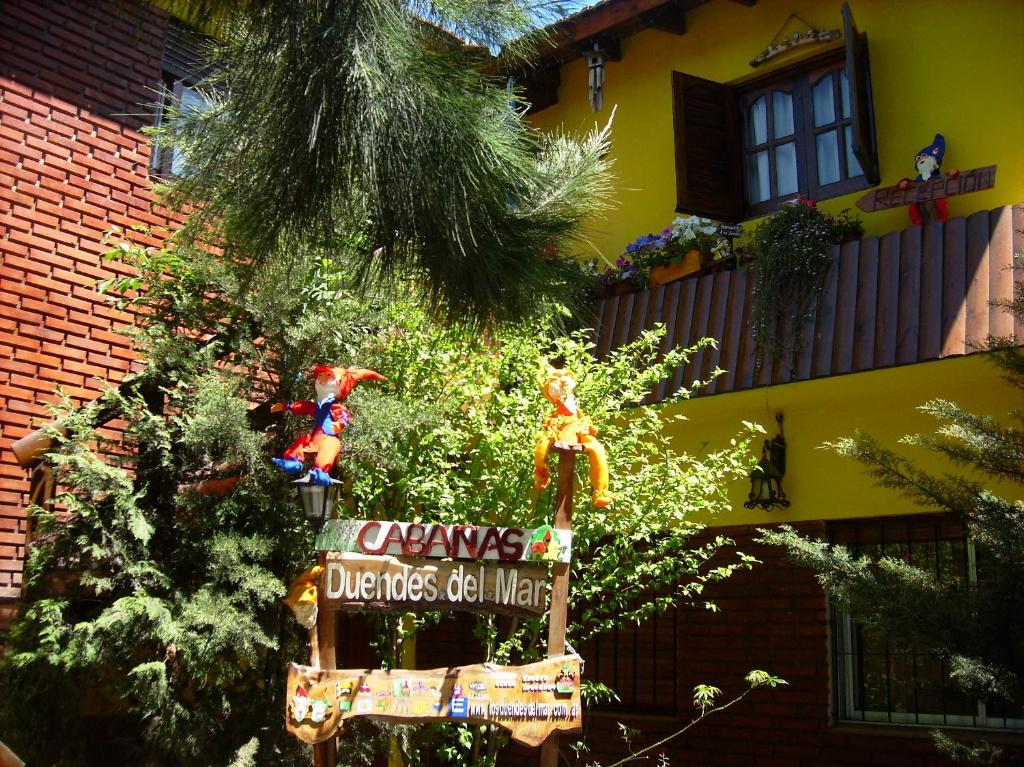 Un árbol de Navidad con un cartel delante de una casa en Los Duendes del Mar en San Clemente del Tuyú